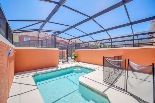 A swimming pool with a glass enclosure, surrounded by orange walls and a clear blue sky. - Mickey Bunk! Value! Resort 5 Mi 2 Disney! 8940 (Kissimmee)