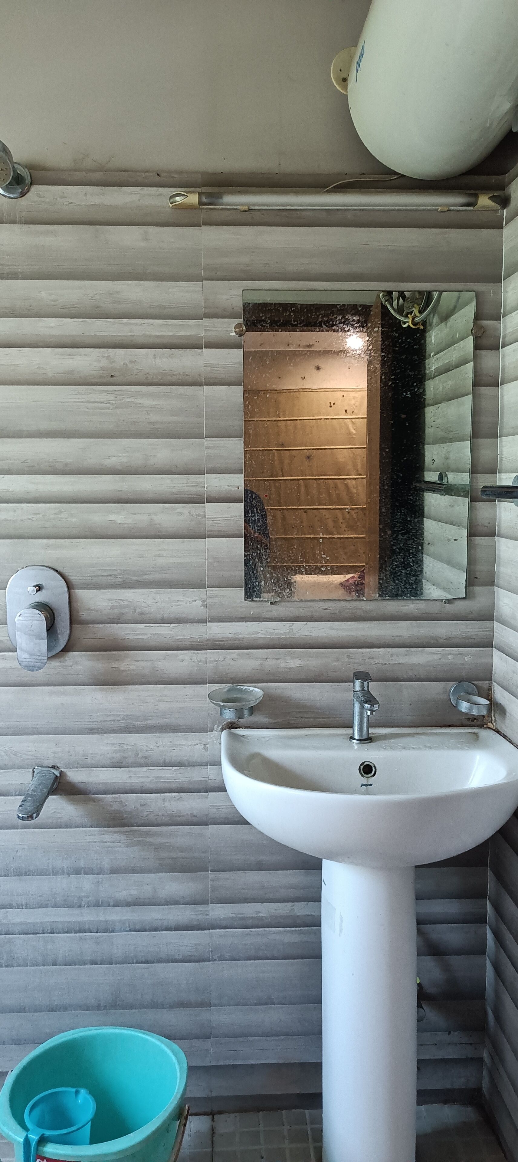 Une salle de bain avec un lavabo blanc, un miroir et un porte-rouleau de papier toilette fixé au mur.