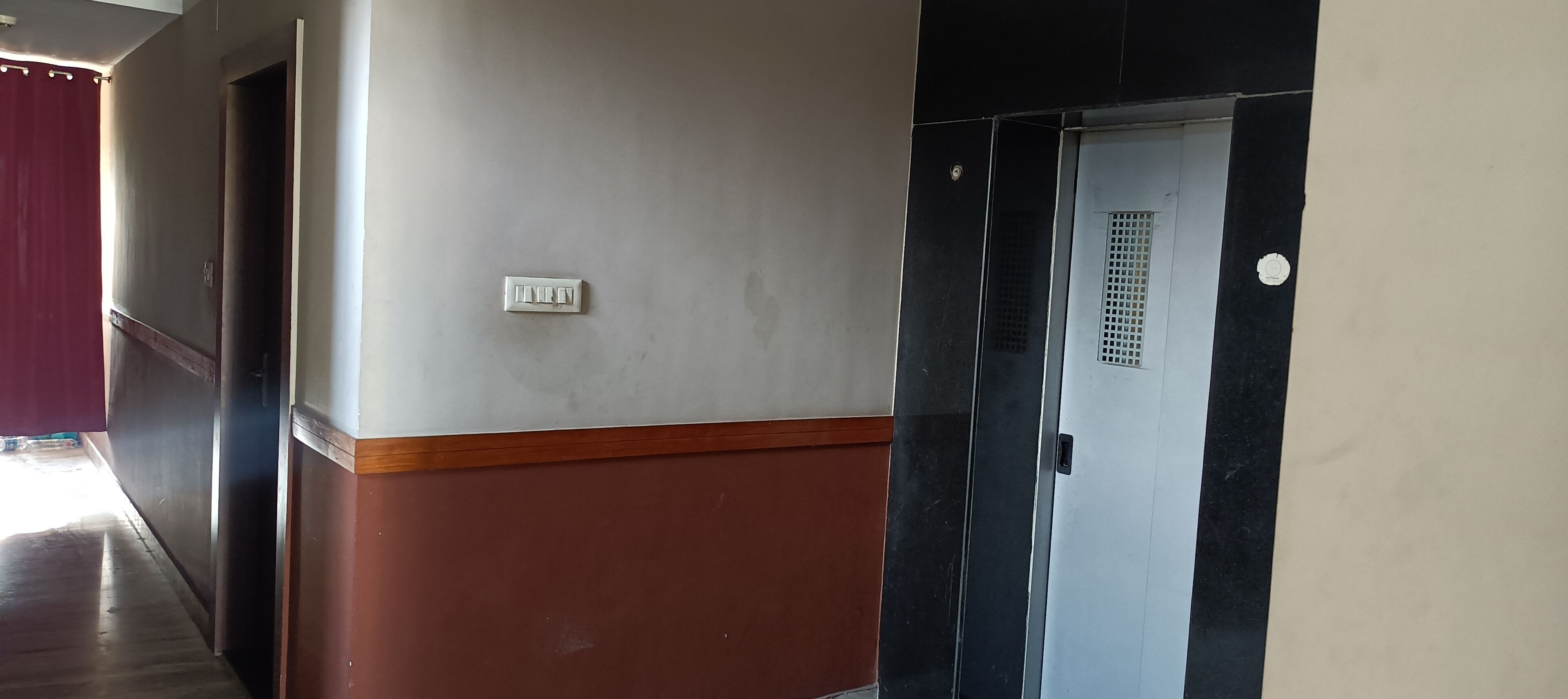 Un pasillo con una puerta, un interruptor de luz y una rejilla de ventilación.