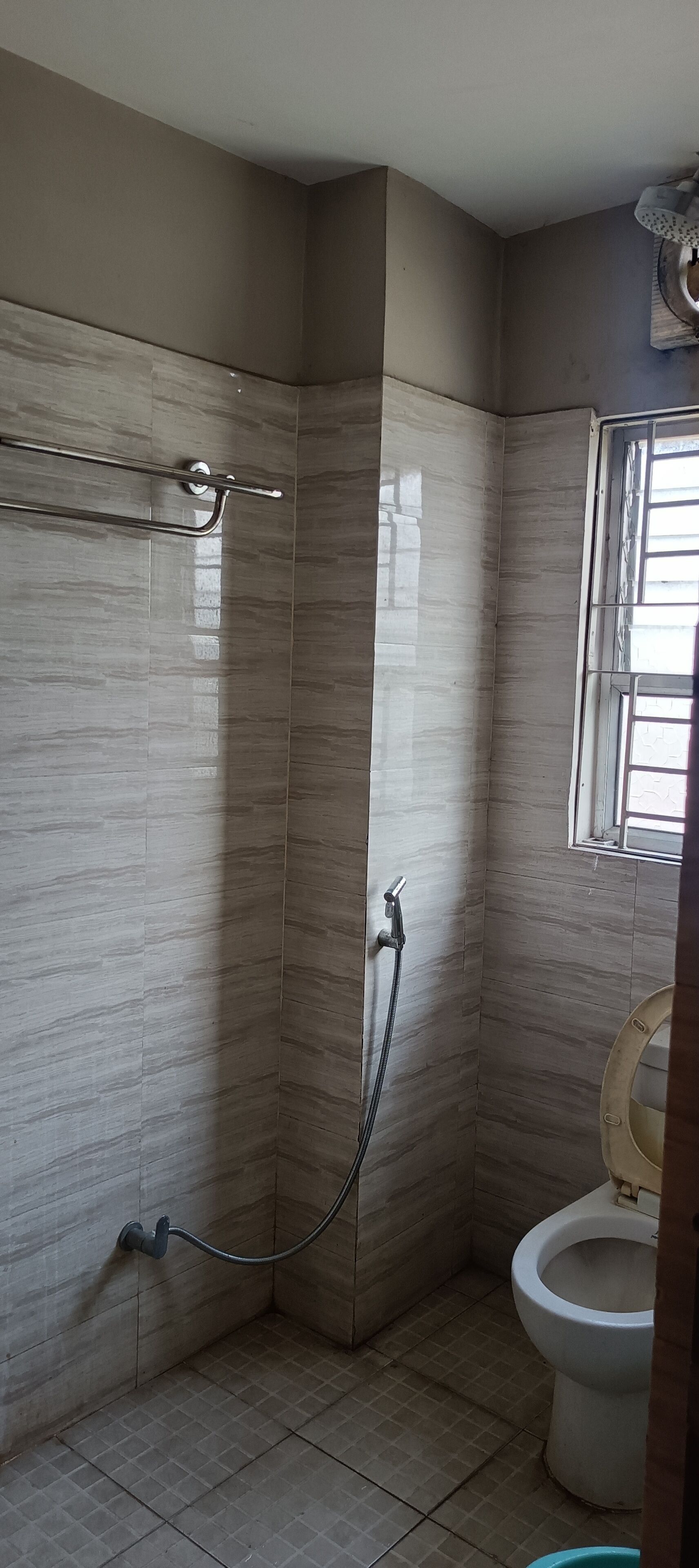 A bathroom with a shower, toilet, and a window.