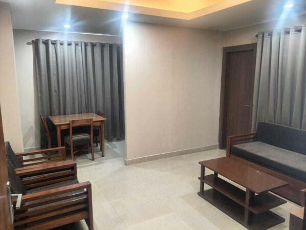 Un salon comprenant un canapé, une table basse, une table à manger avec des chaises et une porte.