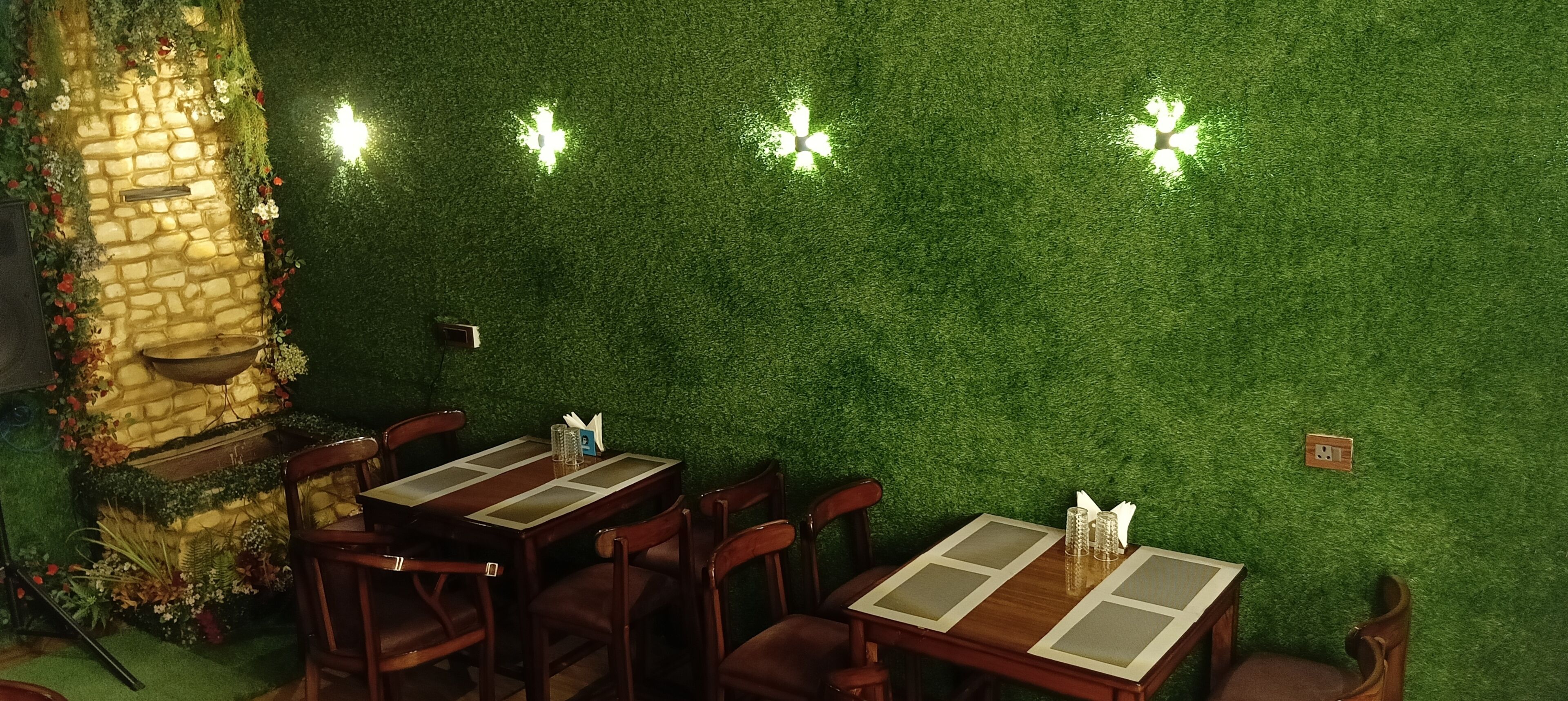 Um restaurante com parede verde, parede de pedra e mesas e cadeiras de madeira.