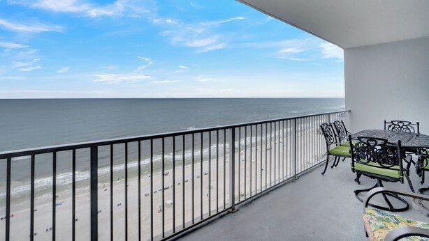 A balcony with a view of the beach and ocean.