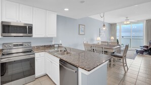 A modern kitchen with white cabinets, stainless steel appliances, and a granite countertop.