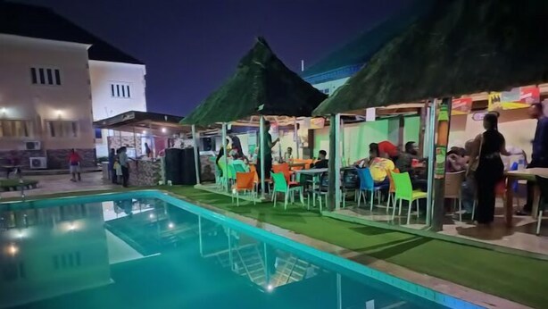 A pool area with outdoor seating and a building in the background. - Fingerprints Hotel (Oba Ile)
