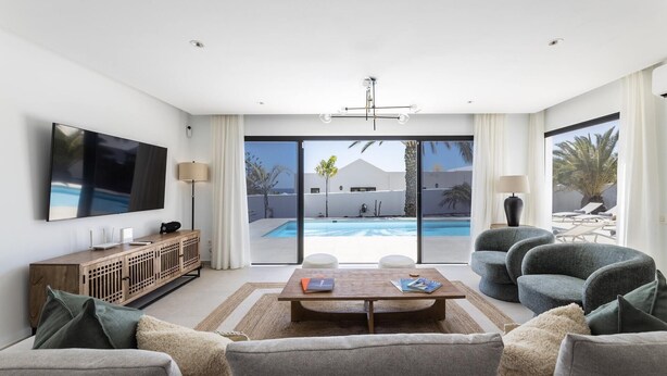 A modern living room with a flat-screen TV, a wooden cabinet, a coffee table, and a sofa. - Villa Bellagio - Rent Villas Lanzarote (Playa Blanca)