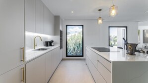 A modern kitchen with a central island, stainless steel appliances, and pendant lighting. - Villa Bellagio - Rent Villas Lanzarote (Playa Blanca)