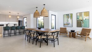 A modern kitchen with a dining area, featuring a wooden table, black chairs, and woven pendant lights. - Villa Bellagio - Rent Villas Lanzarote (Playa Blanca)