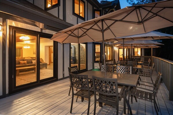 An outdoor patio with a wooden deck, metal chairs, and large umbrellas.