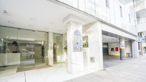 Μια σύγχρονη είσοδος κτιρίου με γυάλινη πρόσοψη, μαρμάρινες κολόνες και μια επιγραφή που αναγράφει «Dream Studios Μπουένος Άιρες».
