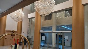 A lobby with a grand chandelier, a revolving door, and a red carpet.
