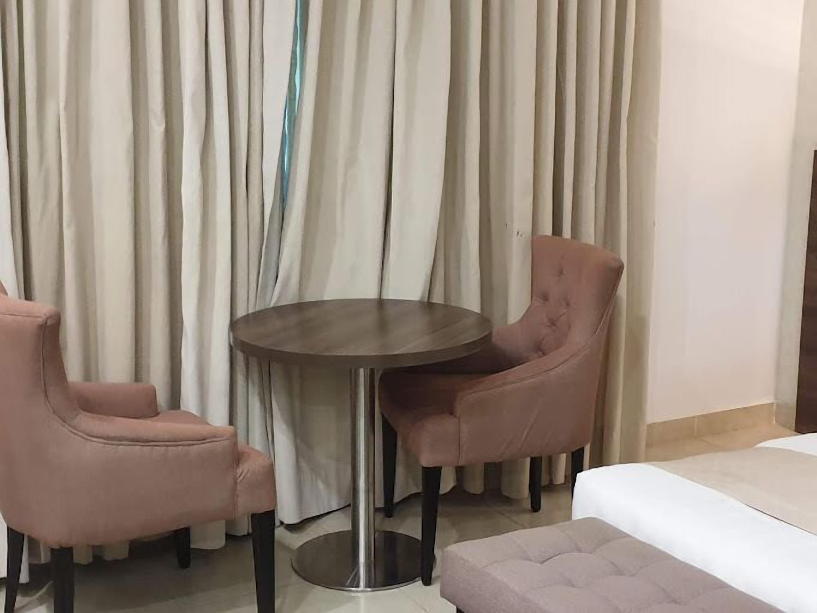A hotel room with a bed, a round table, and two chairs.