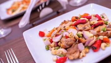 A plate of stir-fried chicken with vegetables and cashews on a white plate.