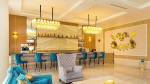 A modern bar area with a marble countertop, blue bar stools, and a chandelier.