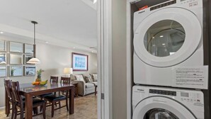 A modern kitchen with a dining area, a washing machine, and a refrigerator.