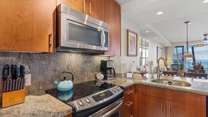 A kitchen with granite countertops, a stainless steel microwave, a stove, and wooden cabinets.