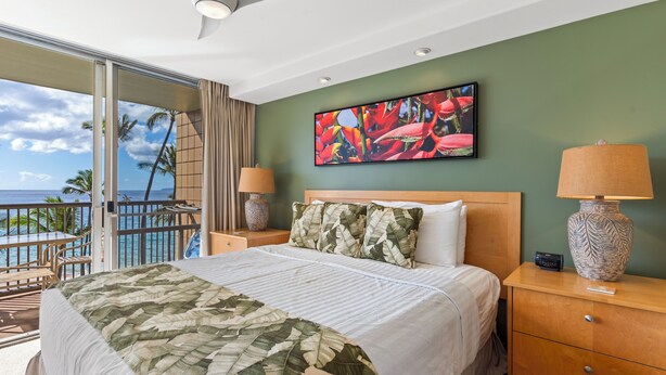 A hotel room with a bed, two bedside tables with lamps, a large window with a view of the ocean, and a tropical-themed painting on the wall.