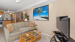 A living room with a sofa, coffee table, TV, and artwork.