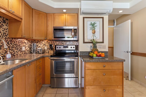 A kitchen with wooden cabinets, a stainless steel oven, a microwave, and a tiled backsplash.
