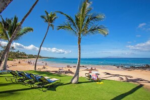 A beach with palm trees, a sandy shore, and a clear blue sky. - Ultimate Oceanfront Paradise-Spectacular Ocean Views-Mana Kai Maui Resort 405C (Kihei, Maui)
