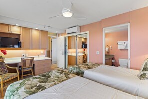 Quarto de hotel com duas camas, uma escrivaninha, uma cadeira e uma televisão.
