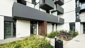 A modern building with balconies, a bike parking area, and a small garden. - Stylish Studio in Jeżyce | Private Parking and Balcony (Poznan)