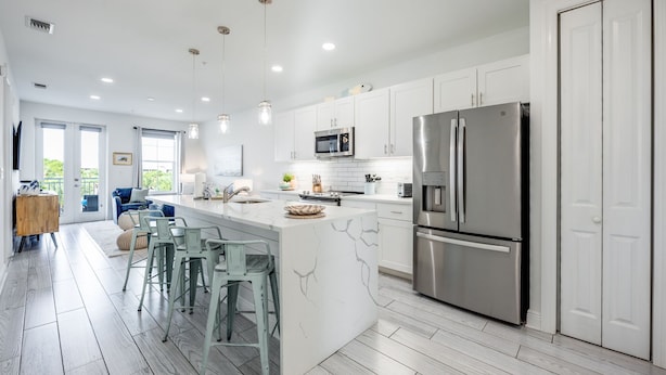 A modern kitchen with white cabinets, stainless steel appliances, and a central island with bar stools.