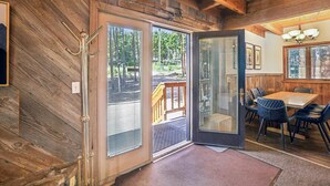 A wooden interior with a dining area, a door leading outside, and a view of the outdoors. - SnowAway-Great Location-Peak 8! (Breckenridge)