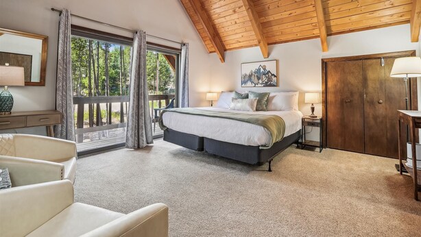 A bedroom with a large bed, a wooden ceiling, a view through a glass door, and a painting on the wall. - SnowAway-Great Location-Peak 8! (Breckenridge)