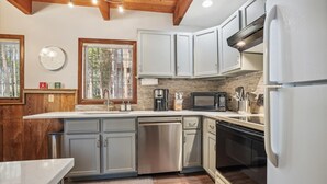 A modern kitchen with white cabinets, stainless steel appliances, and a wooden ceiling. - SnowAway-Great Location-Peak 8! (Breckenridge)