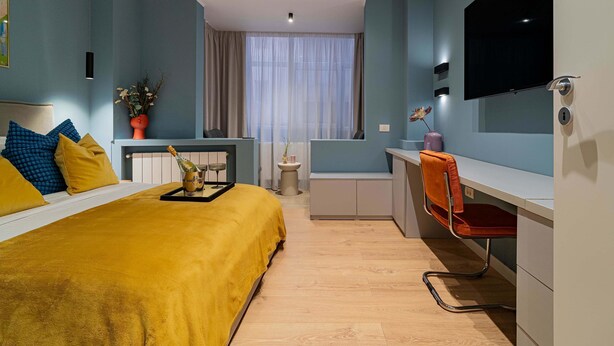 A modern hotel room with a bed, a desk, and a TV. - Celestial Azure Tranquil 1BR Piata Universitatii (Bucharest)