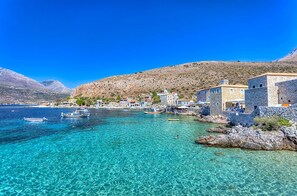 A coastal village with clear turquoise waters, stone buildings, and boats. - Platsa Seaview Retreat - A Stone-built Escape (West Mani)