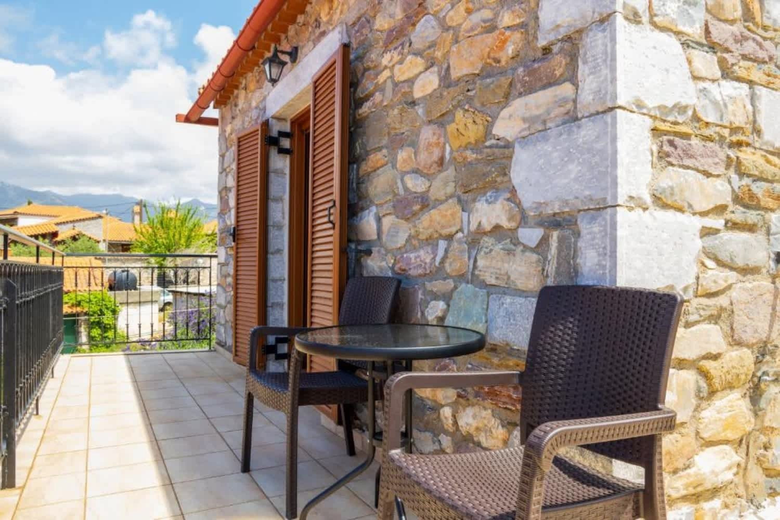 Un bâtiment en pierre doté d’un patio carrelé, d’un espace extérieur aménagé pour s’asseoir et offrant une vue sur les montagnes.