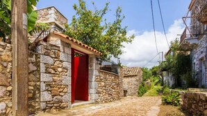 A stone building with a red door, a wooden post, and a stone wall.