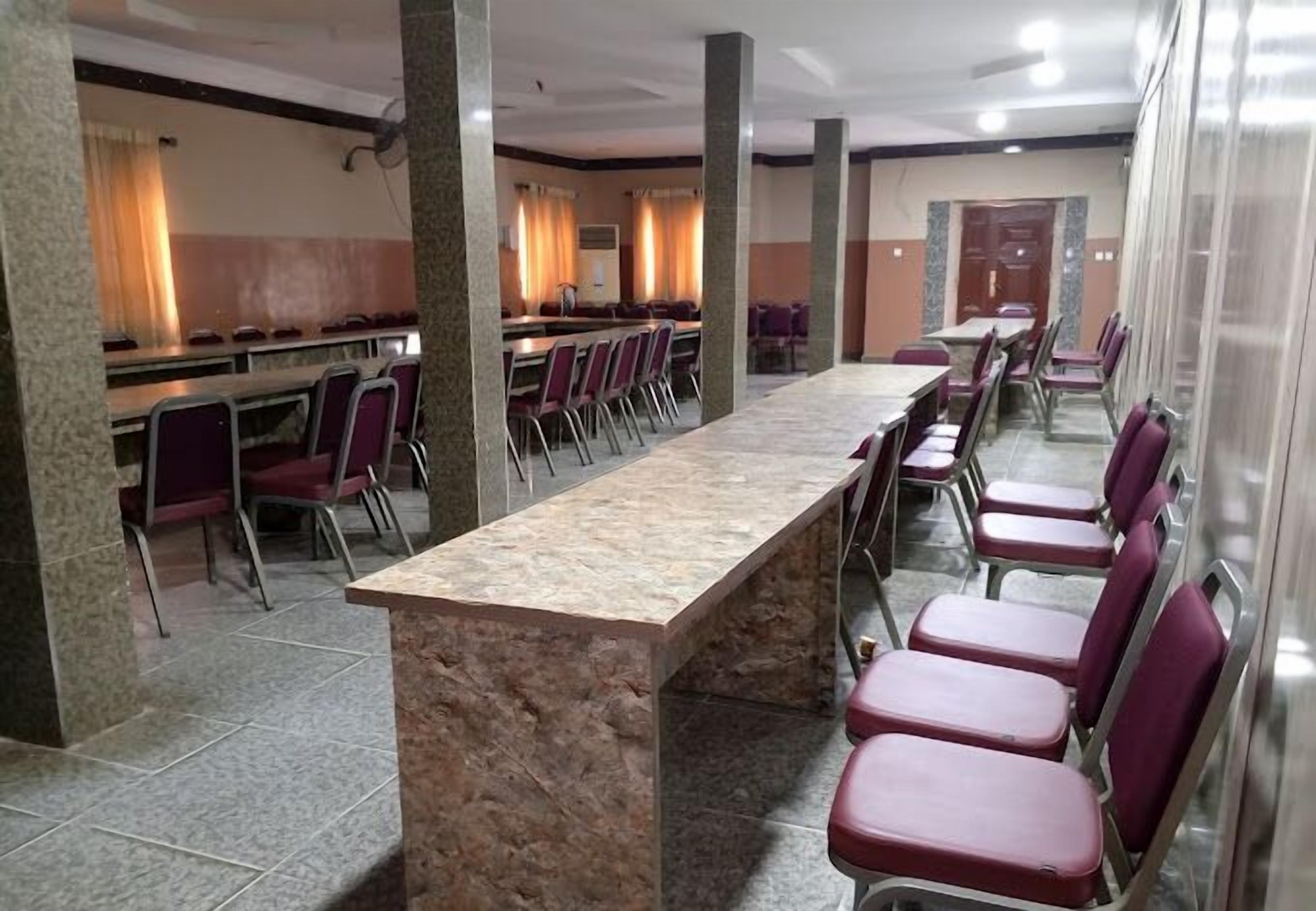 A conference room with a long table and chairs, pillars, and curtains.