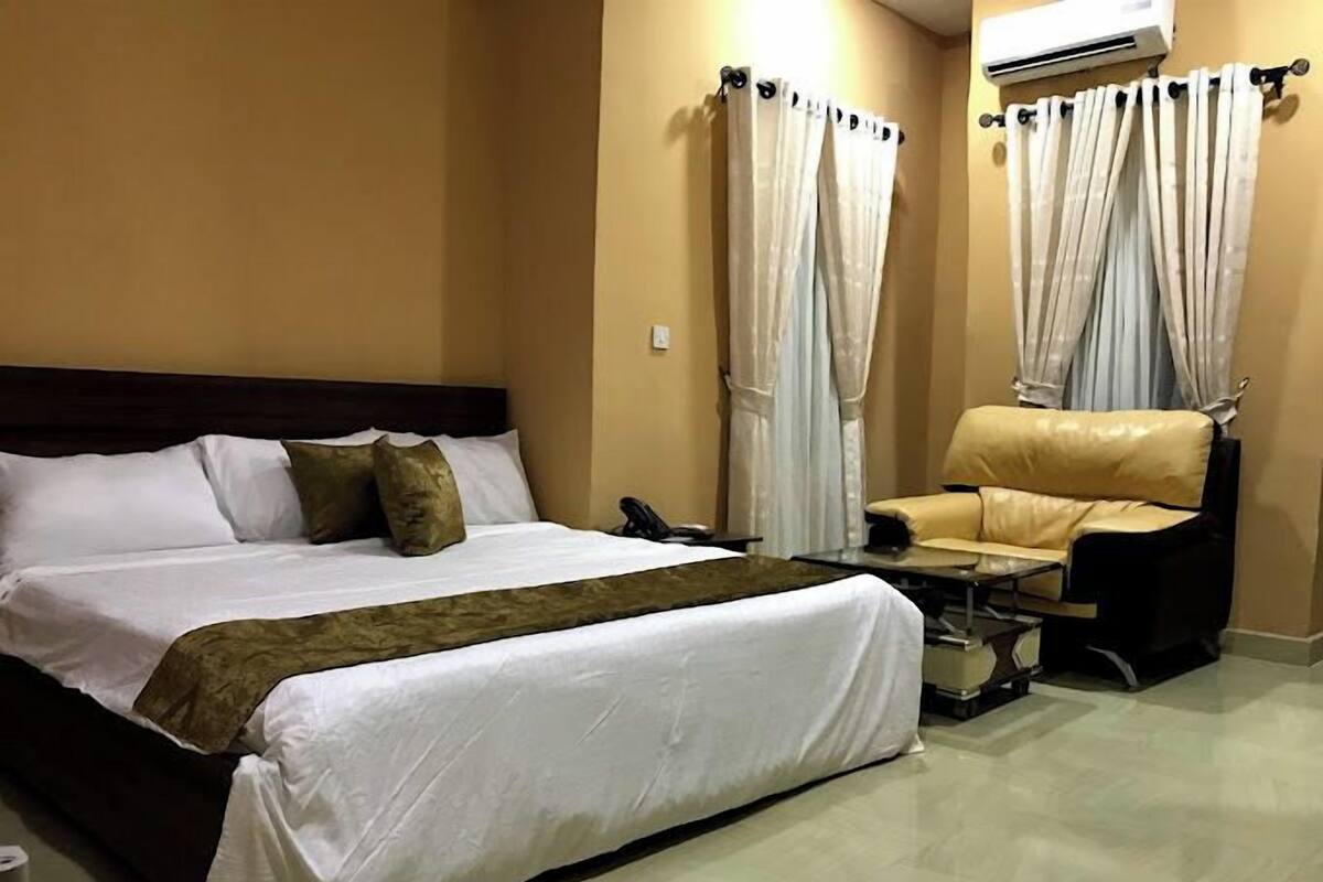 Une chambre d’hôtel équipée d’un lit, d’une chaise, d’une table et d’un appareil de climatisation.