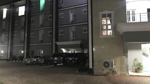 Un immeuble à plusieurs étages devant lequel sont garées plusieurs voitures.
