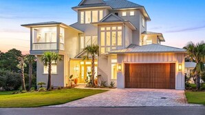 A large, two-story house with a prominent garage and a well-maintained lawn. - Sleeps 18! Private Pool, Spa, LSV/Golf Cart! Gulf Views from Rooftop! Pet Friendly! (Santa Rosa Beach)