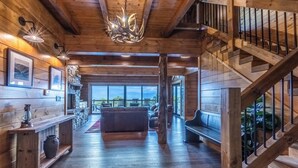A wooden interior with a staircase, a fireplace, and a view through large windows. - High Country Cabin -  Mountain & Fontana Lake Views - Hot Tub (Almond)