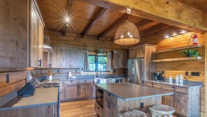 A spacious kitchen with wooden cabinets, a large island, and a hanging light fixture. - High Country Cabin -  Mountain & Fontana Lake Views - Hot Tub (Almond)