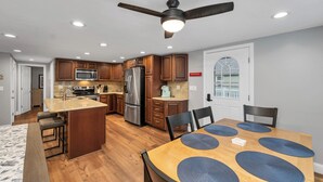 A modern kitchen with wooden cabinets, stainless steel appliances, and a central island with bar stools.