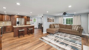 A modern kitchen with wooden cabinets, a stainless steel refrigerator, and a bar area with stools.
