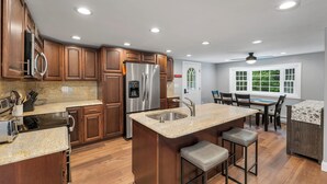 A modern kitchen with wooden cabinets, stainless steel appliances, and a granite countertop.