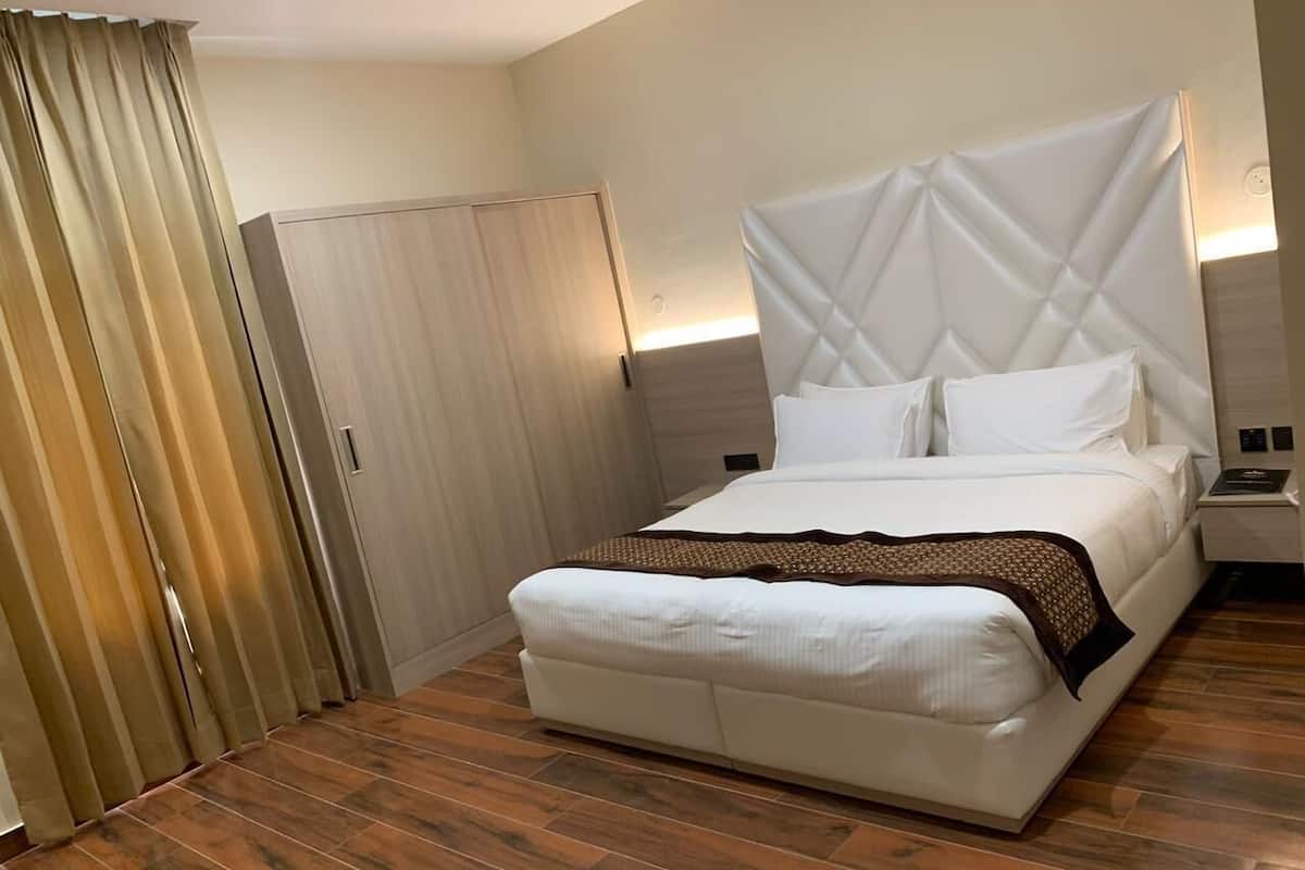 A hotel room with a bed, a nightstand, a wardrobe, and a curtain.