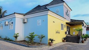 Un edificio a due piani con facciata blu e gialla, condizionatori d'aria e una scala che conduce all'ingresso.