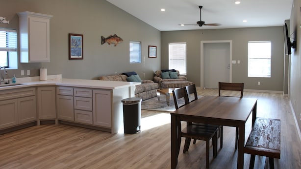 A spacious kitchen with a dining area, a ceiling fan, and a large window. - 308 Copano - Vast open design, modern & can accommodate big groups (Port Mansfield)