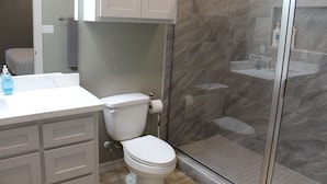 A bathroom with a toilet, a sink, and a shower. - 308 Copano - Vast open design, modern & can accommodate big groups (Port Mansfield)