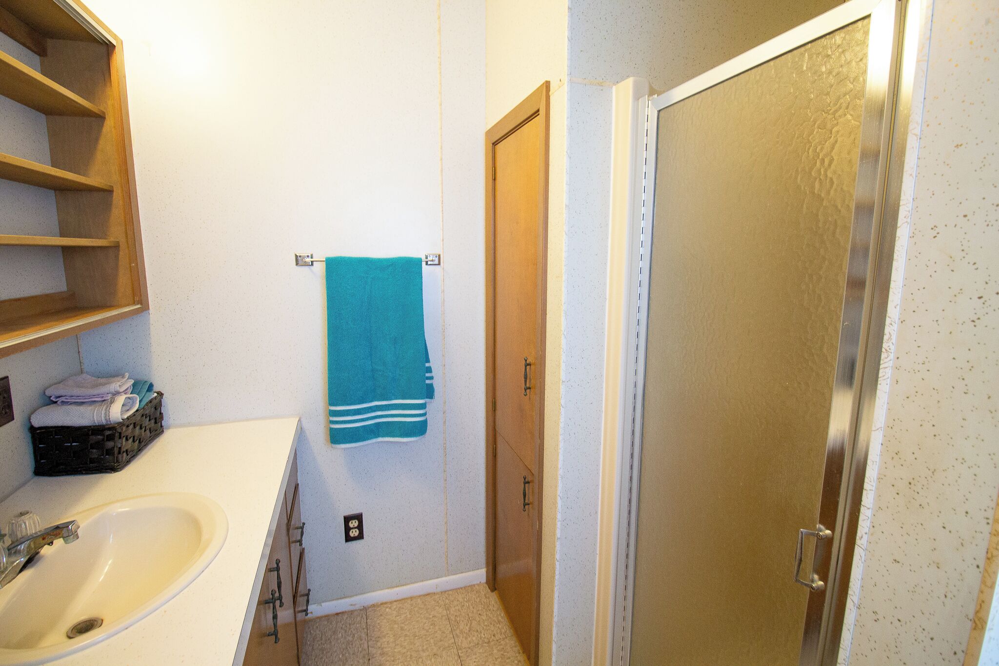 A bathroom with a sink, a towel rack, and a shower door.