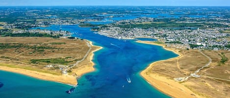 Ein Luftbild einer Küstenstadt mit einer weiten Bucht, einem Strand und Wohngebieten.
