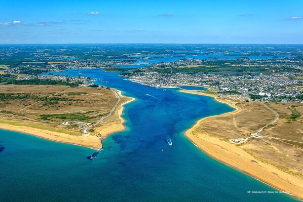 An aerial view of a coastal town with a large bay, a beach, and residential areas.